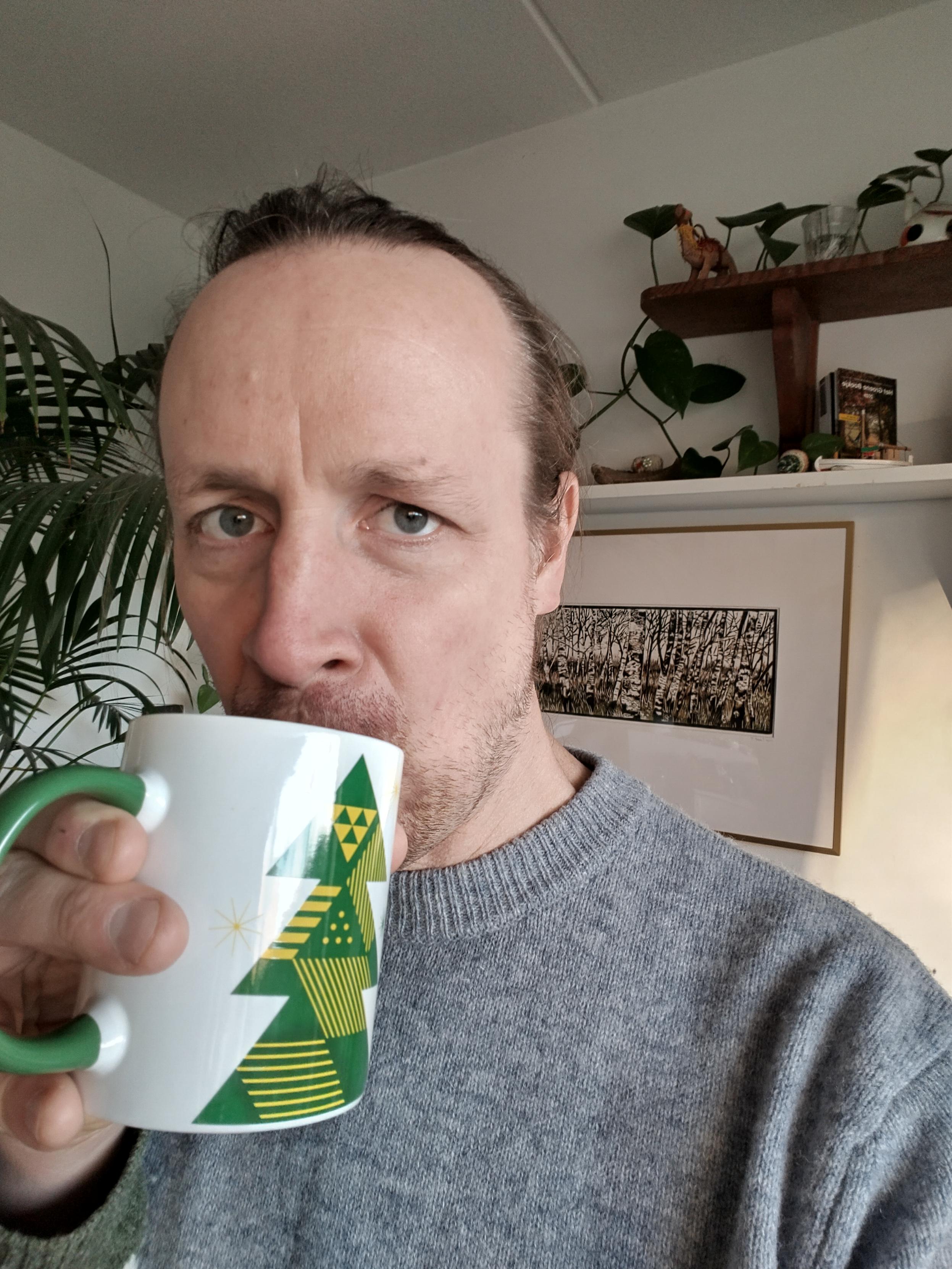 Evert die een slok koffie drinkt uit zijn kerstmok